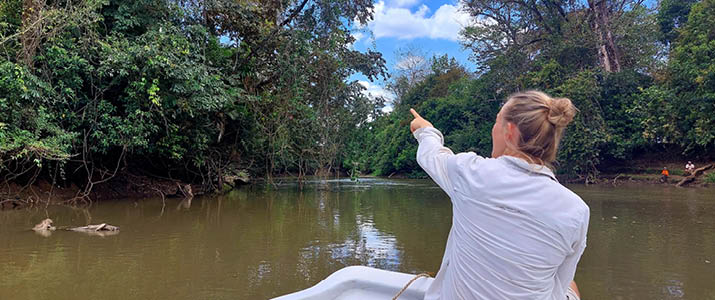 une personne à l'avant du bateau en train de regarder les arbres le long de la riivère, elle pointe quelque chose
